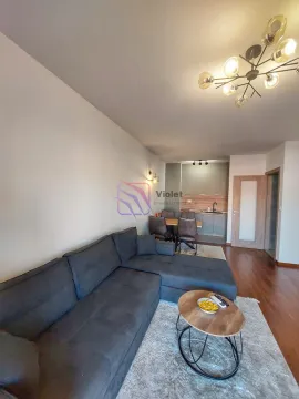 Living room with a sofa, dining area, and kitchen in the background. - image 5