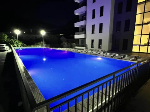 Noćni prikaz bazena ispred stambene zgrade sa ležaljkama. - image 8