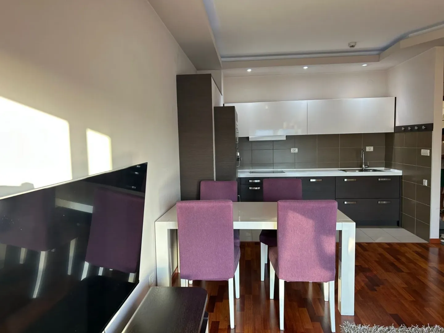Living room with dining area and a fitted kitchen in the background.