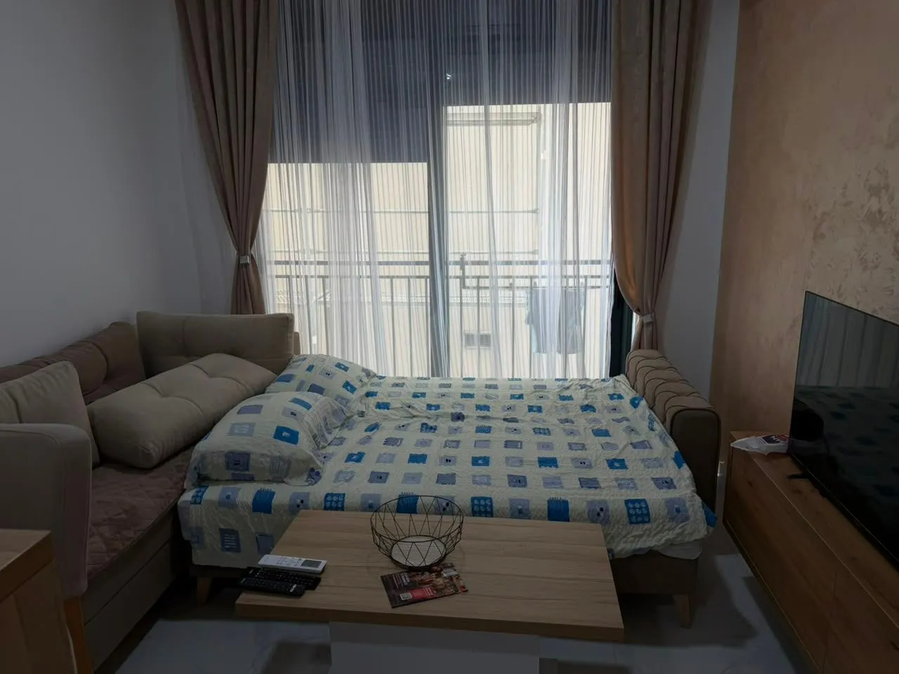 Bedroom with a bed, sofa, TV, and balcony access.
