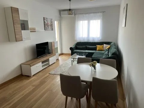 Bright living room with a green corner sofa, dining table, and TV unit. - image 2