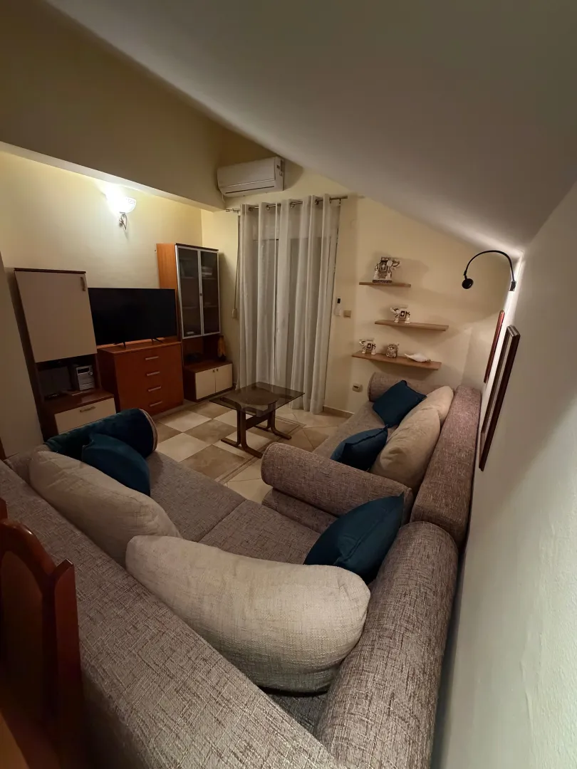 Namještena dnevna soba sa garniturom i TV komodom u potkrovlju.