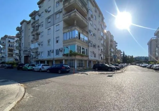 Eksterijer stambene zgrade sa parkingom i ulicom.