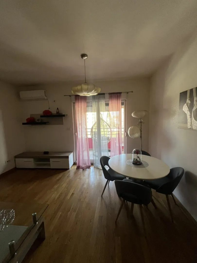 Trpezarijski dio sa okruglim stolom, stolicama i izlazom na balkon.