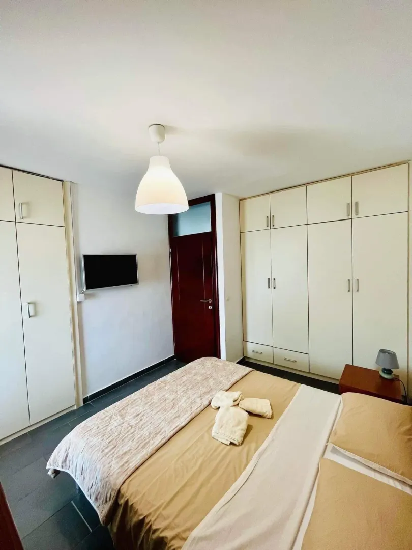 Furnished bedroom with a double bed, wardrobes, and a TV.