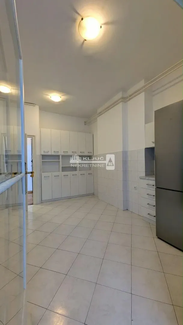 Spacious kitchen with white units and a refrigerator.