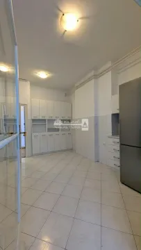 Spacious kitchen with white units and a refrigerator. - image 15