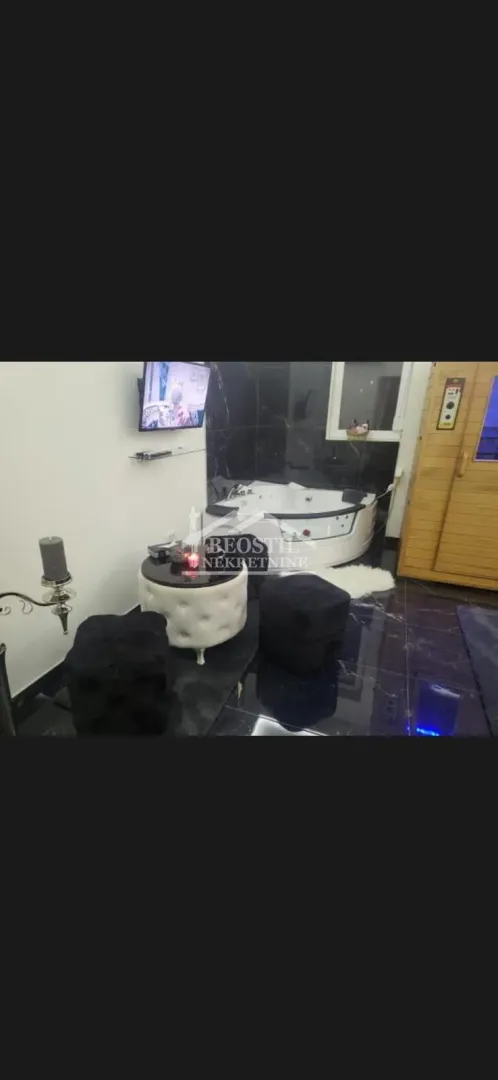 Bathroom with a whirlpool bathtub, small table, ottomans, and a built-in sauna.