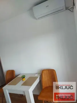 Trpezarijski sto sa stolicama i klima uređaj na zidu. - image 10