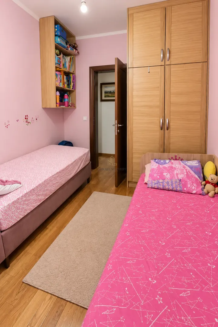 Dječja spavaća soba sa dva kreveta, velikim ormarom i zidnim policama.