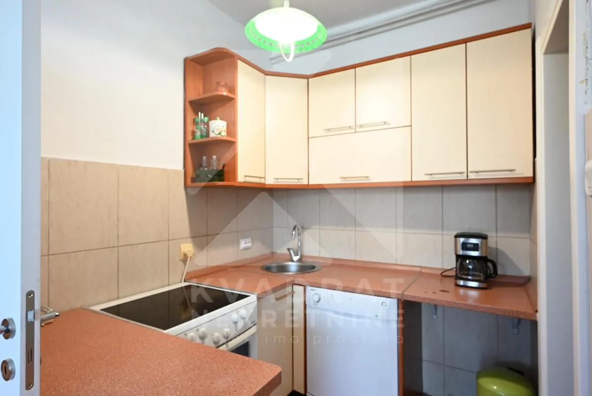 Compact kitchen with countertops, sink, and built-in stove.