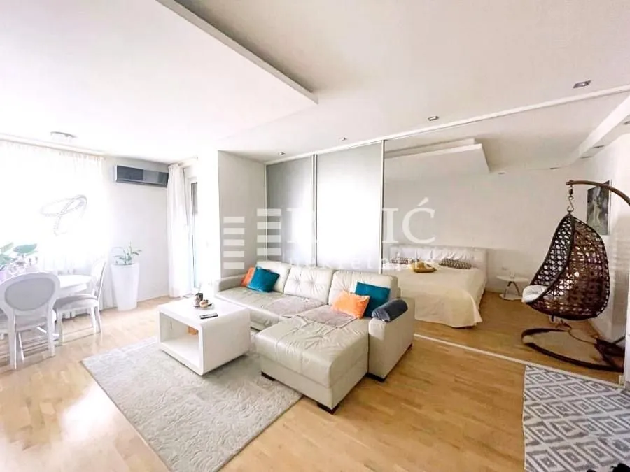 Living room with sofa and dining table, overlooking the bedroom.