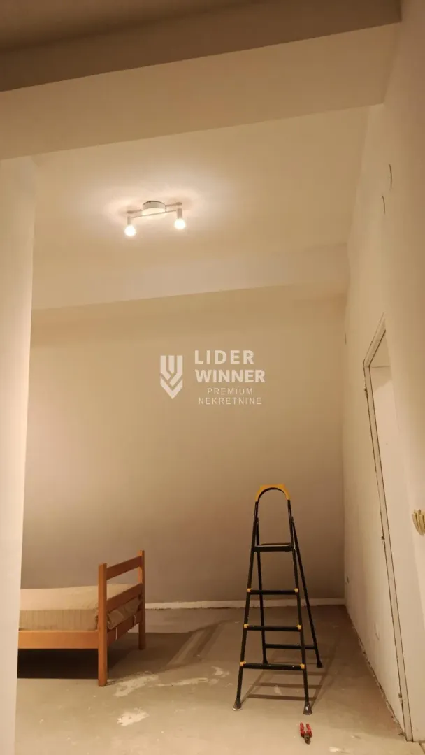 Prazna prostorija u toku renoviranja sa krevetom i merdevinama.