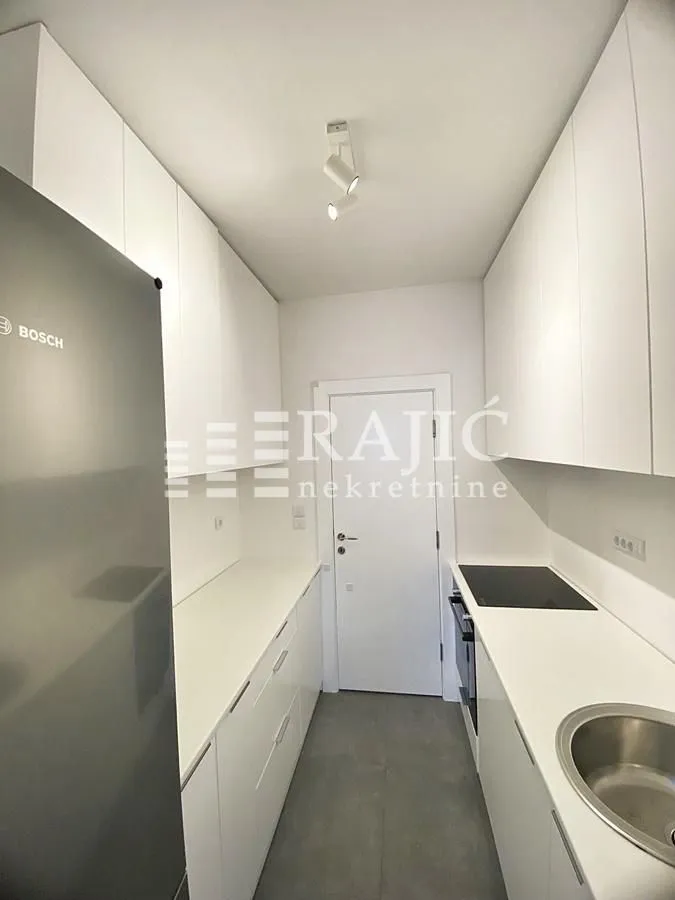 Modern white kitchen with built-in appliances and a refrigerator.