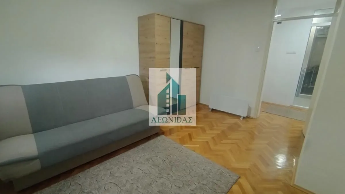 Living room with a sofa, wardrobe, and parquet flooring.