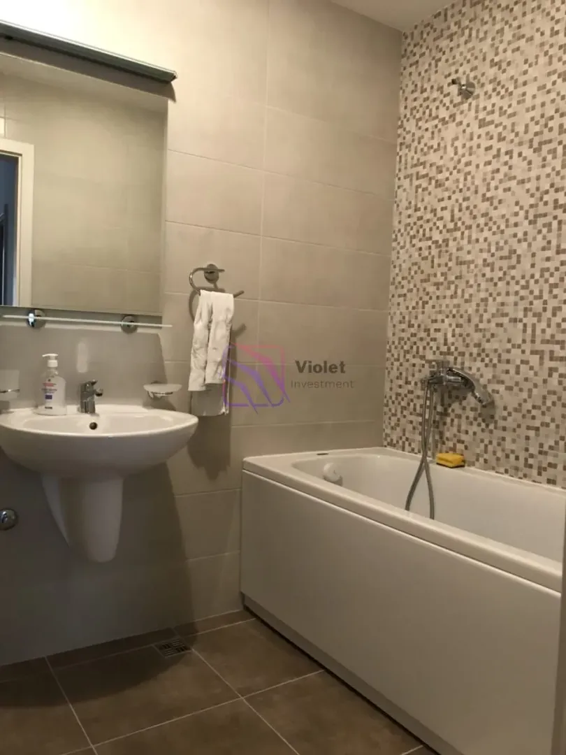 Bathroom equipped with a washbasin, mirror, and bathtub with mosaic tiles.