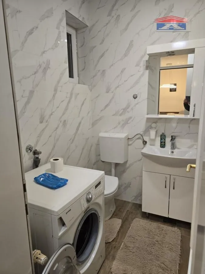 Kupatilo opremljeno umivaonikom, WC šoljom i veš mašinom.
