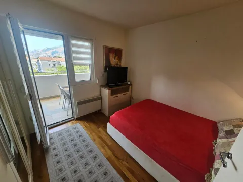 Manja spavaća soba sa krevetom, TV-om i izlazom na terasu. - image 5