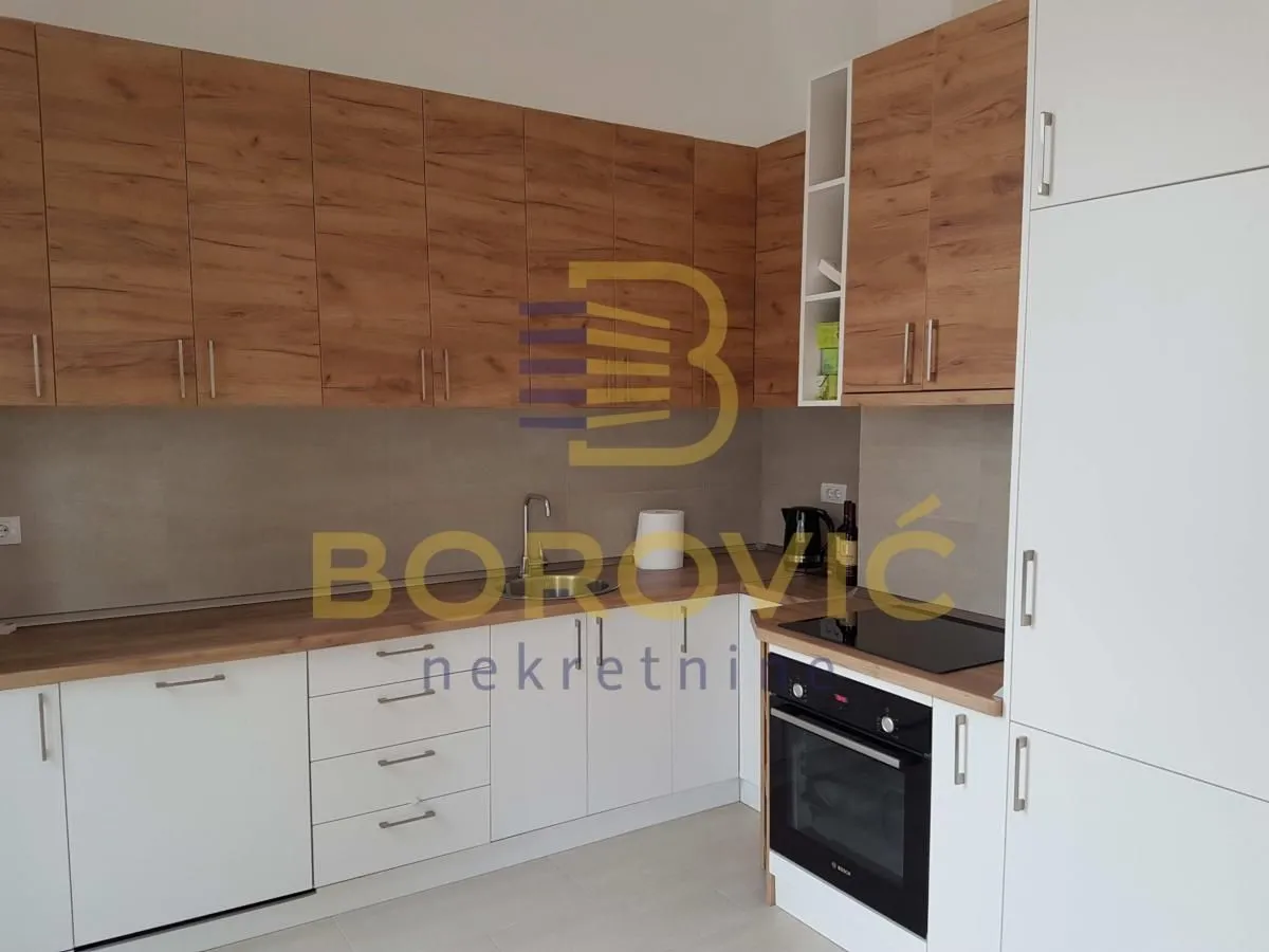 Modern kitchen with white cabinets and wood-grain finish.