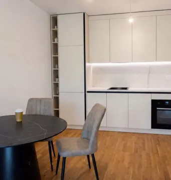 Modern kitchen with a dining area and white cabinetry. - image 4