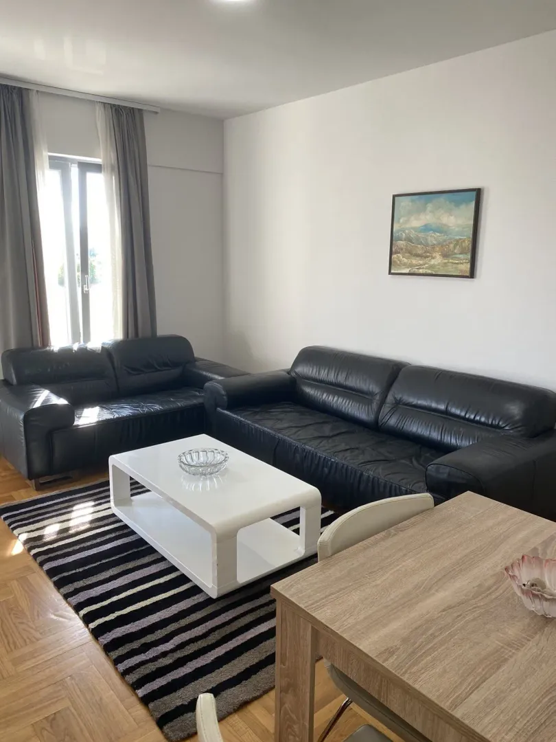Bright living room featuring black leather sofas and a white coffee table.