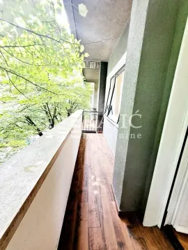 Long balcony space with wooden flooring and a view of trees. - image 19