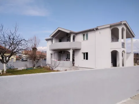 A two-story house with a fenced yard under a blue sky. - image 19
