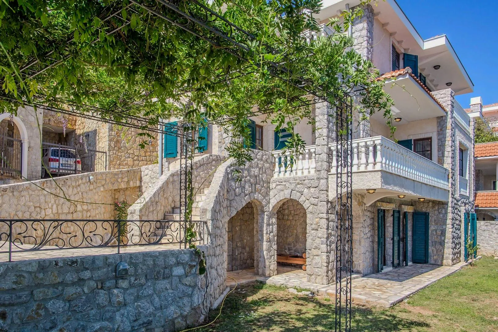 Eksterijer kuće sa kamenom fasadom, terasom i dvorištem.