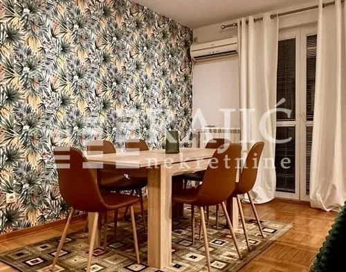 Dining room with a wooden table, chairs, and wallpaper on the wall.