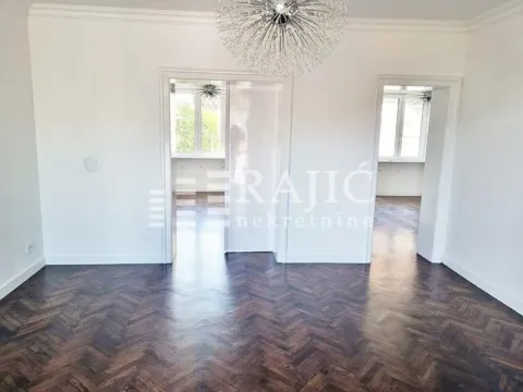 Spacious empty room with dark parquet flooring and white walls. - image 2