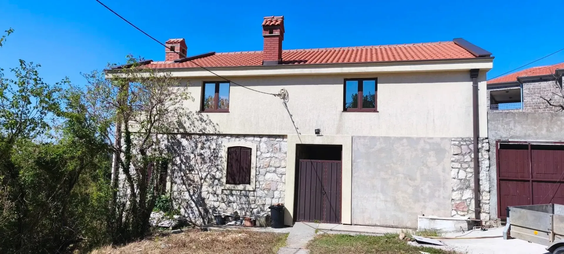 Front side of the house with stone facade and yard.