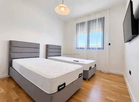 Bedroom with two single beds and a wall-mounted TV. - image 7
