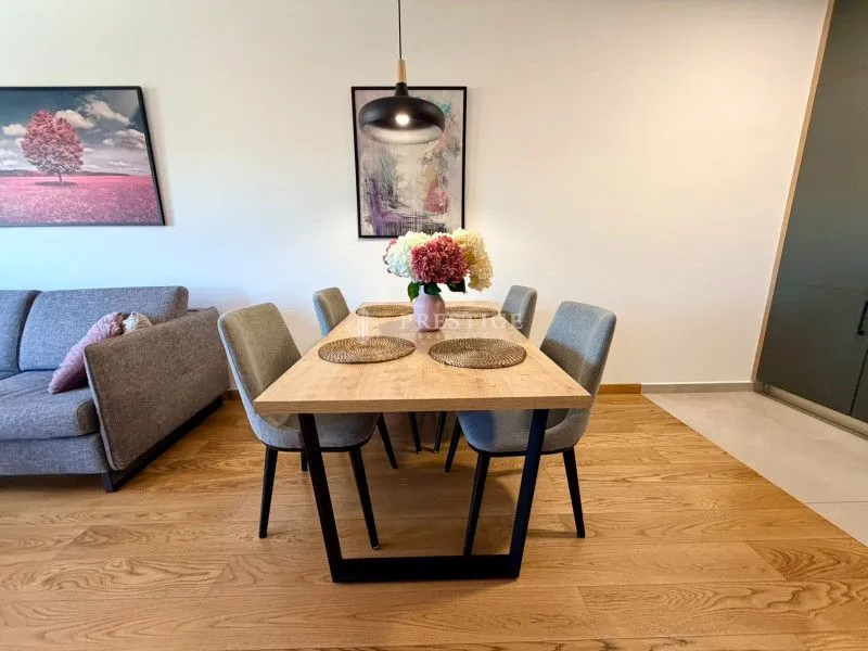 Modern dining area with a wooden table and grey chairs as part of the living room.