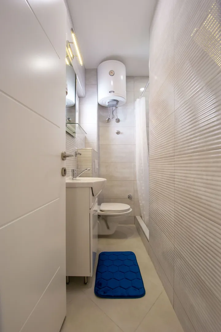 Small bathroom with a sink, toilet, shower cabin, and water heater.
