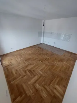 Prazna prostorija sa parketom i pripremljenim delom za kuhinju sa zidnim pločicama. - image 5