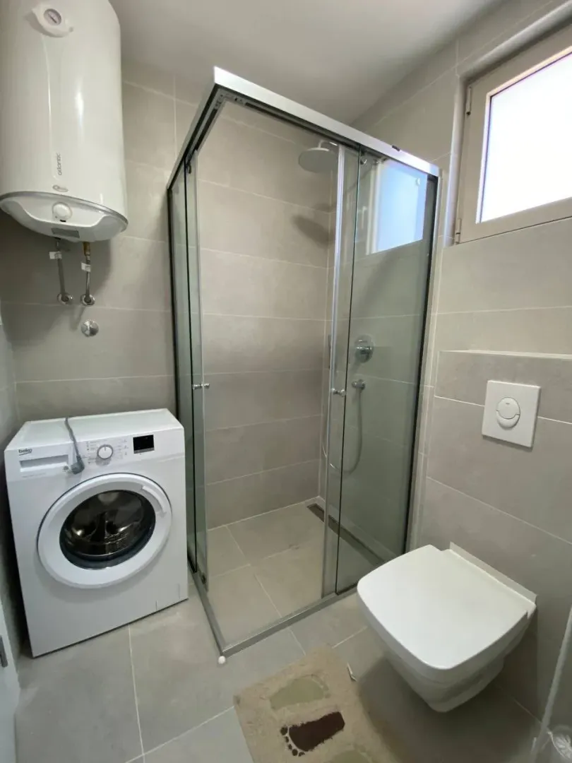 Modern bathroom equipped with a shower cabin, washing machine, and water heater.