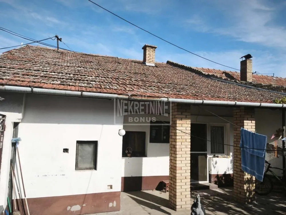 Pogled na dvorište i stariju kuću sa krovom od crepa.