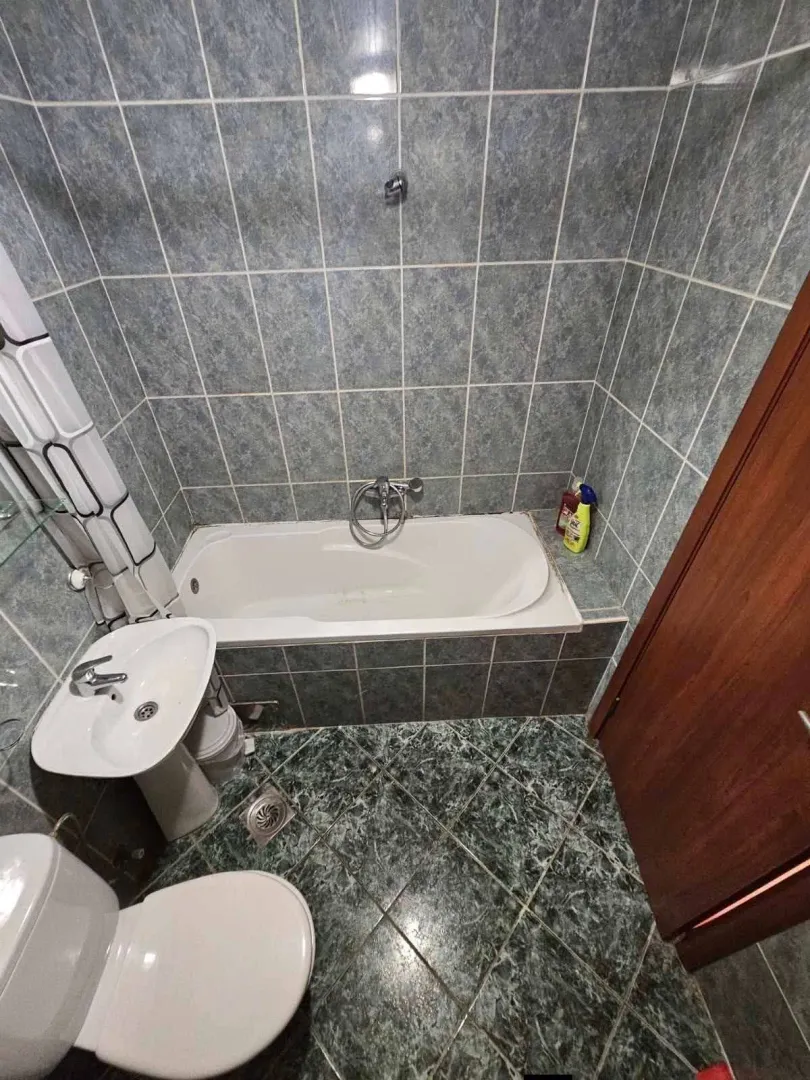 Kupatilo opremljeno kadom, umivaonikom i toaletom sa pločicama u plavim tonovima.