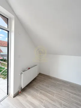 Empty attic room with white walls, wooden flooring, and balcony doors. - image 12