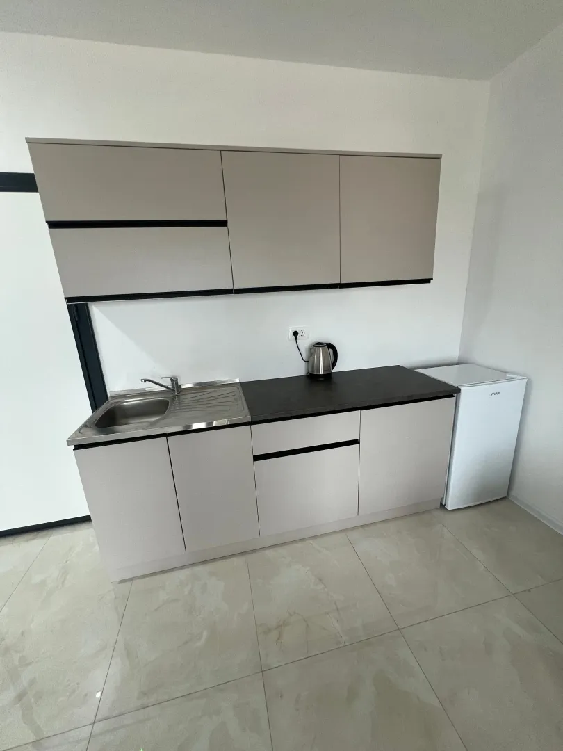 Small kitchen with a sink, cabinetry, and refrigerator.