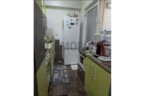 Manja kuhinja sa zelenim frontovima i frižiderom na kraju prostorije. - image 2
