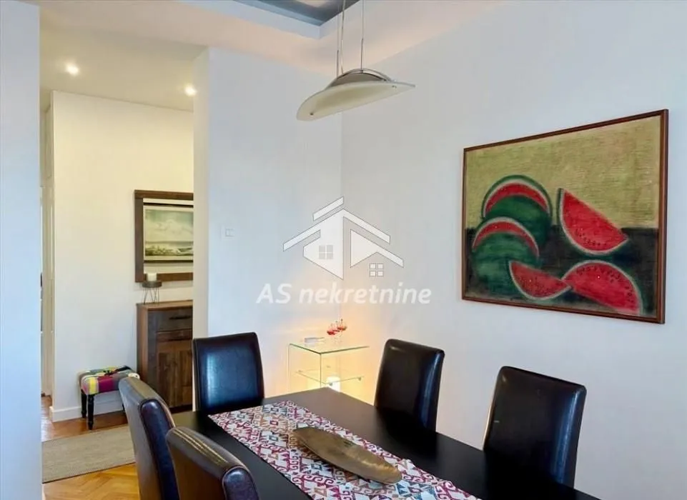 Dining area with a dining table and chairs, decorated with a painting on the wall.