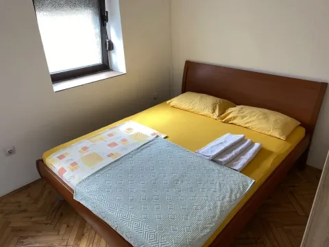 Jednostavna spavaća soba sa bračnim krevetom i žutom posteljinom. - image 3