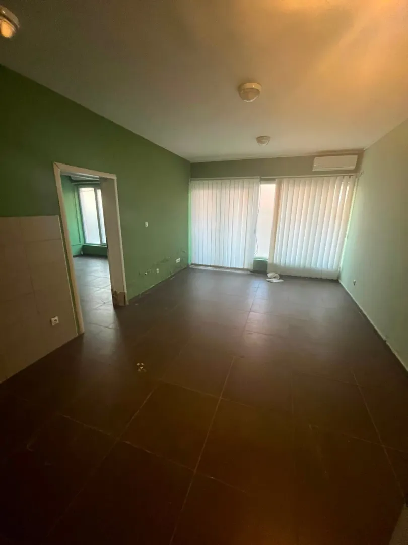 Empty room with dark floor tiles and green walls.