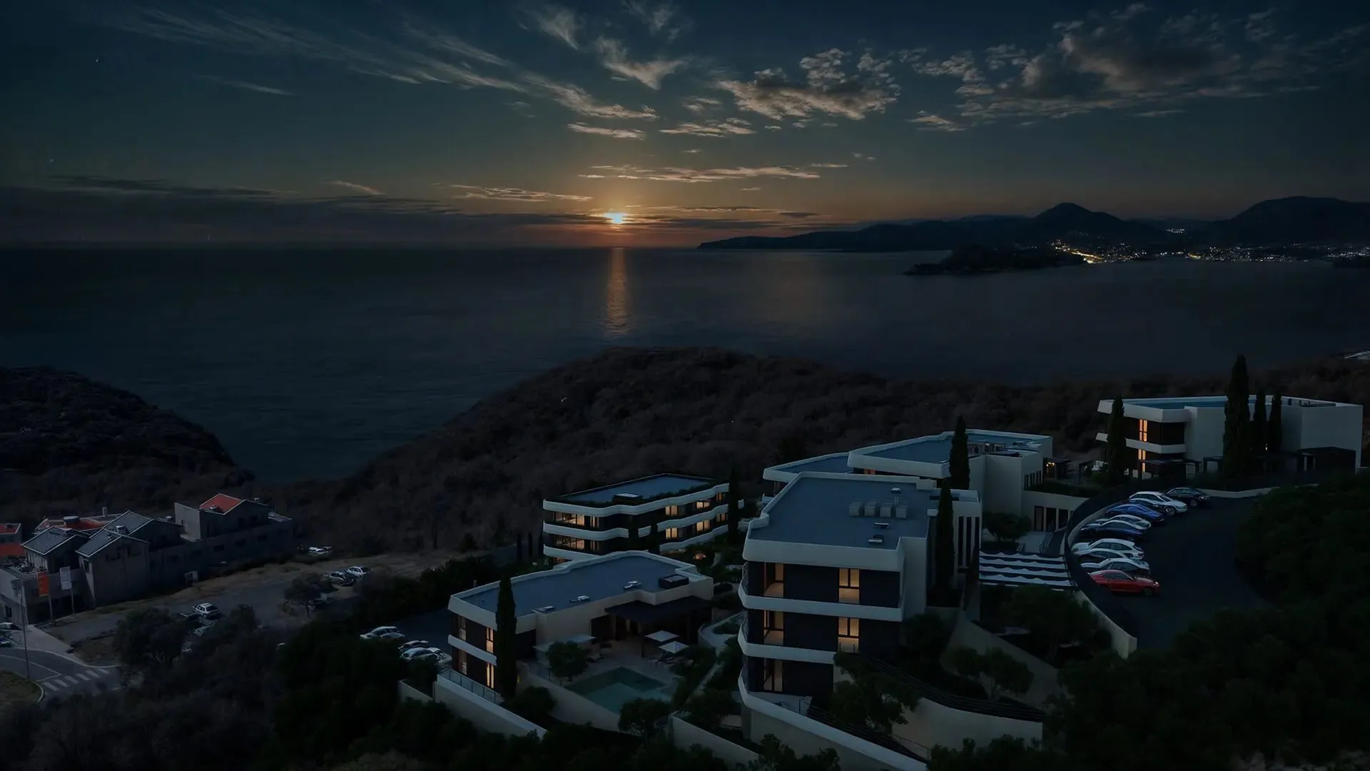 Pogled iz vazduha na kompleks zgrada u sumrak sa pogledom na more.