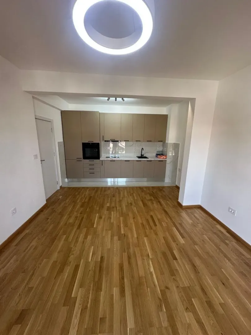 View of an empty kitchen with built-in cabinetry and hardwood flooring.
