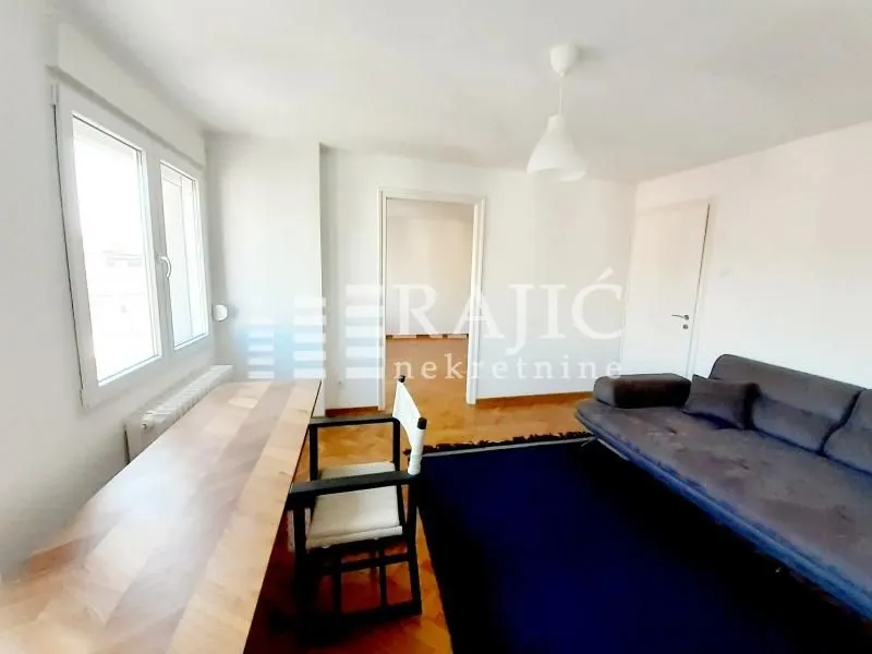 Living room with a sofa, desk, and parquet flooring.