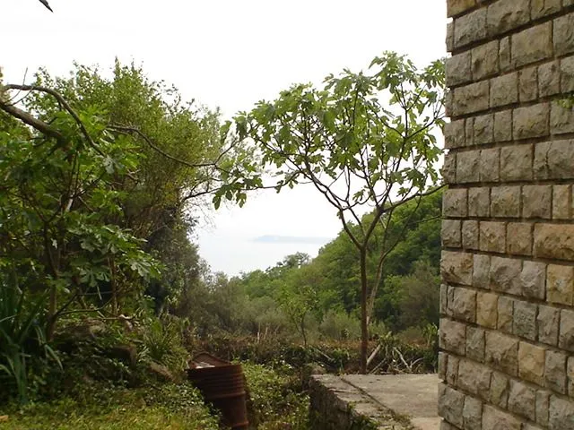 Vanjski dio kamene kuće sa dvorištem i pogledom na more.