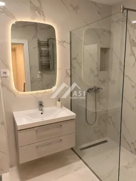 Savremeno opremljeno kupatilo sa umivaonikom i tuš kabinom obloženim mermernom keramikom. - image 5