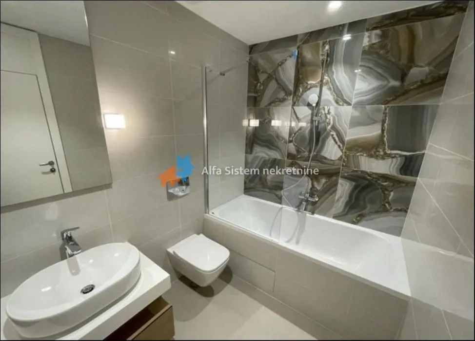 Modern bathroom with a bathtub, washbasin, and toilet.